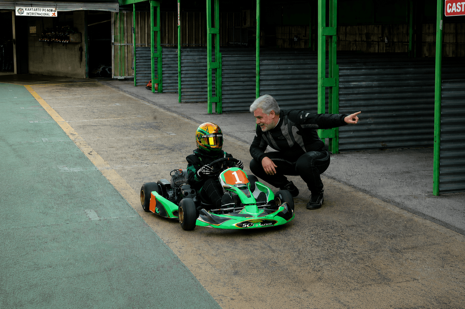 Instructor guiando a un joven piloto de karting en el circuito